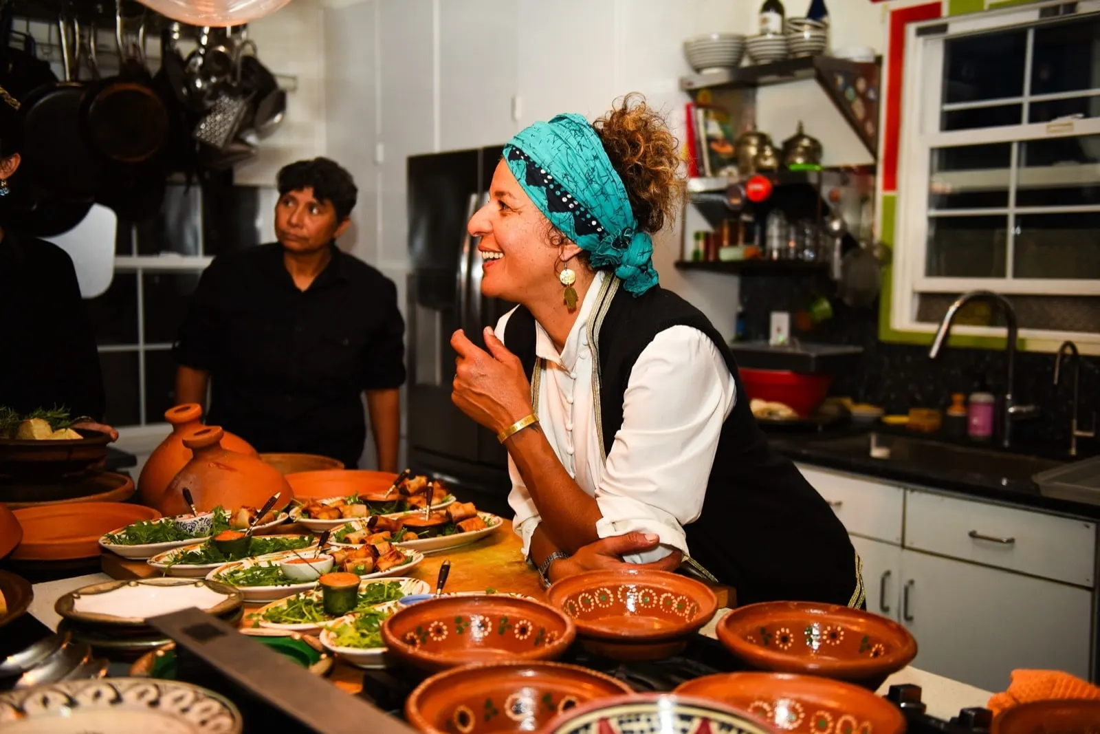 Chef Yasmina Ksikes laughing in the kitchen over terracotta tagines and briouats