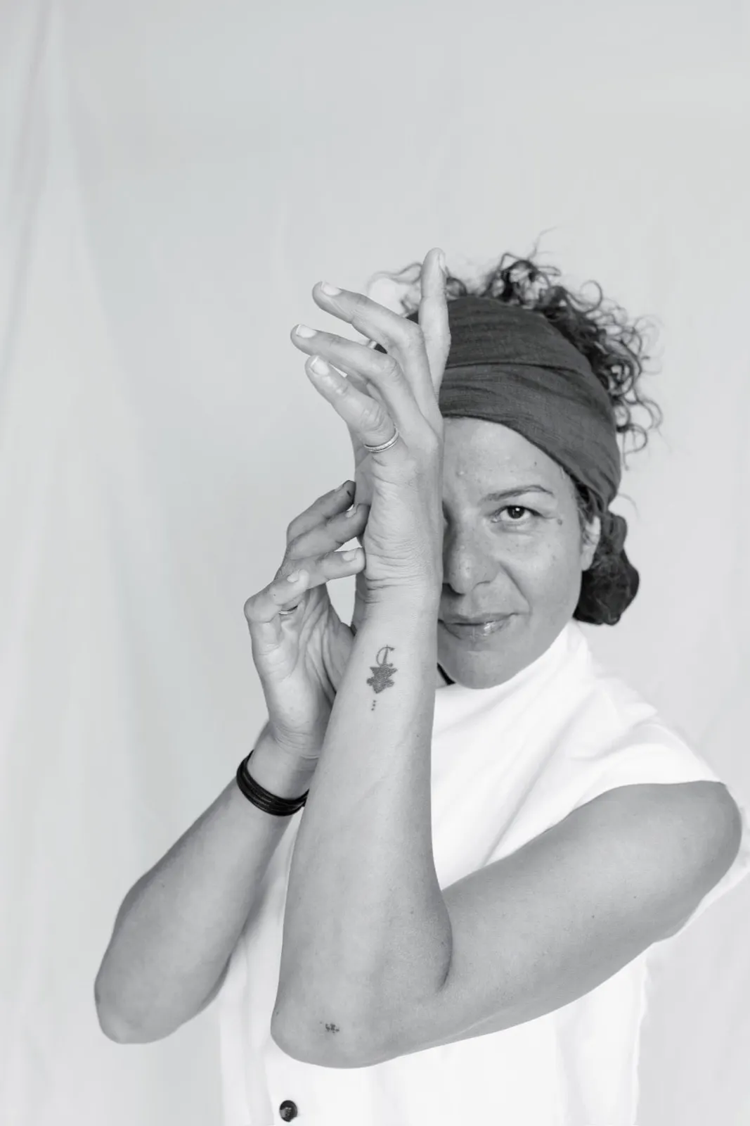 Chef Yasmina Ksikes framing her face with her hands, black and white portrait