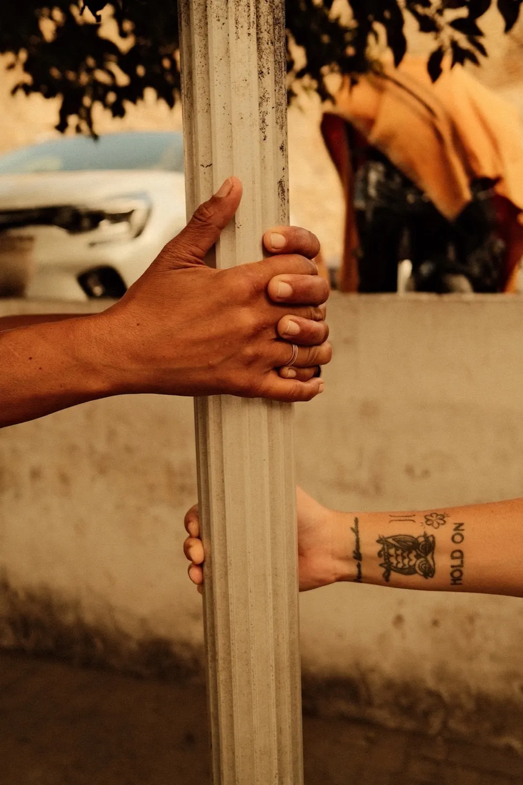 Two hands holding the same pole, one with a hold on tattoo