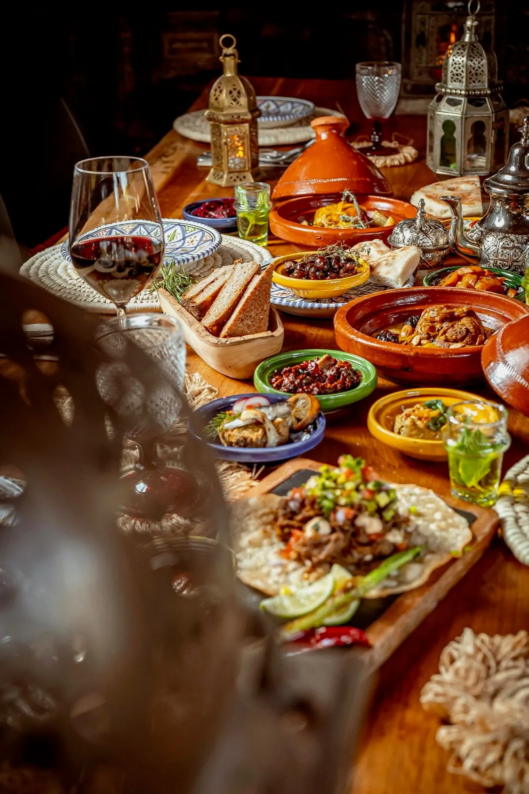 Restaurant table of Moroccan mezze, tagines and lanterns